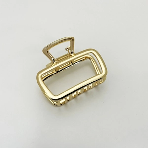 Close-up of golden rectangular hollow shark clip with metallic spring and polished finish