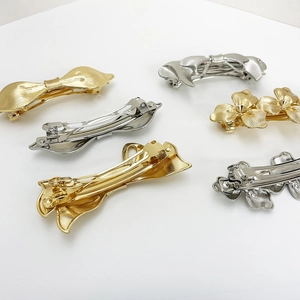 Detailed view of gold and silver alloy bow and flower hair clips with spring clasps