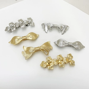 Set of 6 gold and silver metal hair clips with floral and bow designs and brushed texture
