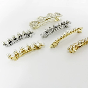 Close-up of pearl hair clips with heart rhinestones and silver/gold plating details