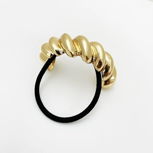 Detail view of a golden twisted spiral metal accent with black elastic hair band
