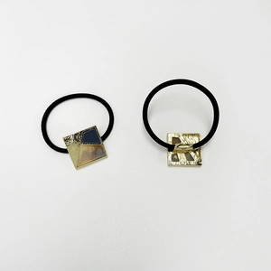 Detail showing two elastic hair ties with square gold metal and leopard resin charms