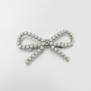 Detailed view of elegant pearl bow hair clip with silver spring mechanism and polished finish