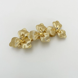Detailed macro view of golden alloy spring hair clip with three textured flower petals