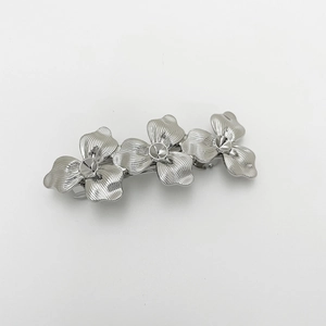 Detail shot of bright silver alloy hair clip featuring three textured flower patterns