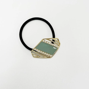 Detailed close-up of retro hair tie featuring gold metal frame and green enamel center