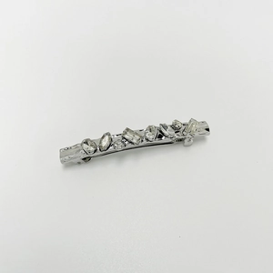 Close-up of silver spring hair clip with multi-shape clear crystals on white background