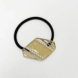 Close-up of elegant hair tie with beige enamel gold metal buckle and white pearls