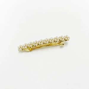 Detailed macro view of elegant faux pearl flower clusters on a gold metal spring hair clip