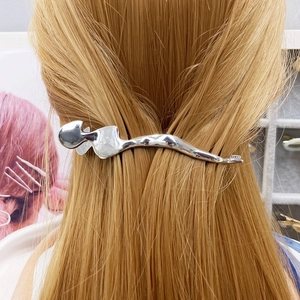 Macro detail of silver abstract body alloy hair clip worn on light golden hair