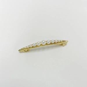 Close-up of golden hair clip with elegant white pearls in a minimalist French style