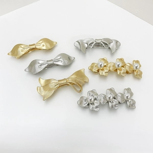 Elegant gold and silver bow and flower hair clips with pearls on a white background