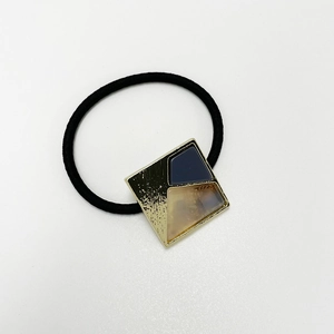 Close-up of elastic hair tie with square gold metal and marble resin detail