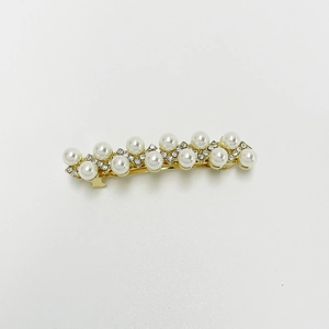 Detailed macro of gold-plated hair clip with double-row pearls and sparkling rhinestones