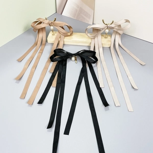 Detailed view of long tassel bow hair clips with pearls in black, brown and beige colors