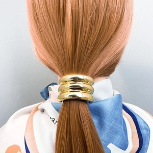 Close-up of three-layer gold metal hair cuff for ponytail on stylish model