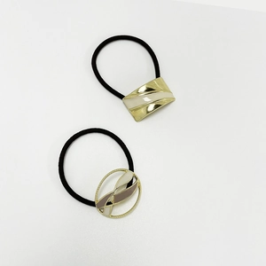 Close-up of golden metal hair ties with beige enamel and textured resin details