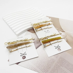 Three-piece gold hair clip set with amber resin and rhinestones on a white card