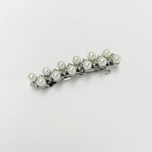 Close-up of pearl hair clip with silver metal base and sparkling crystal accents