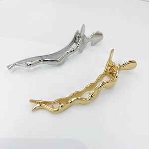 Close-up of irregular wavy alloy hair clips in polished gold and silver finishes