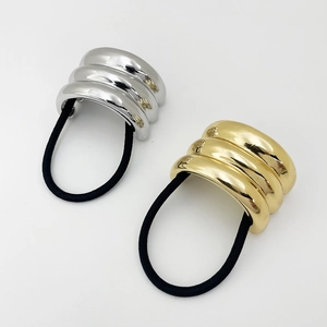 Macro shot of U-shaped metallic hair rings with triple-ridged texture in gold and silver