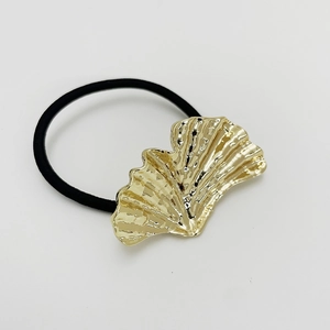 Vue détaillée d'une breloque en forme de feuille de ginkgo dorée sur élastique noir