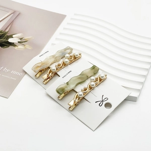 Elegant four-piece resin and pearl hair clip set on a white decorative display
