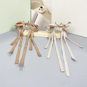 Detailed view of elegant ribbon bow hair clips with long streamers and pearl pendant accents
