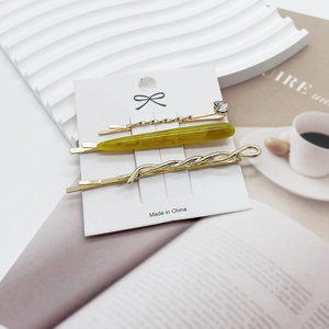 Detailed view of three luxury hair clips on a card featuring gold metal and green marble textures
