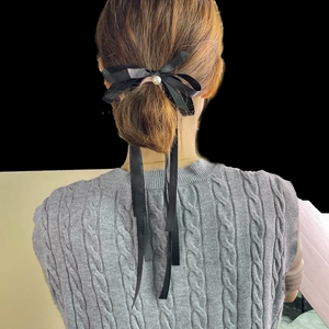 Elegant black satin bow hair clip with white pearl detail on low ponytail style