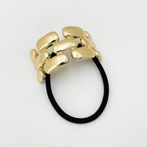 Close-up of gold chain link metal ornament on black elastic hair tie minimalist style