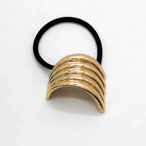 Close-up of golden U-shaped metal hair tie with wavy texture and black elastic cord