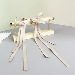 Close-up of champagne pink bow hair clip with elegant long ribbons and white pearl detail