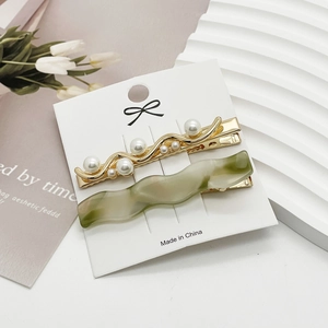 Detail of elegant pearl hair clips and green resin barrettes on display card