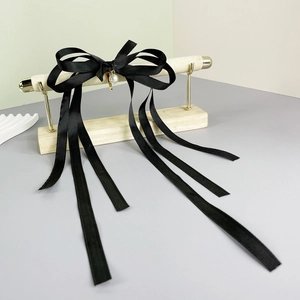 Close-up of black ribbon bow hair clip with a pearl pendant and long tassels