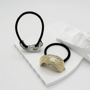 Detailed view of silver and gold irregular textured metal charms on black hair ties