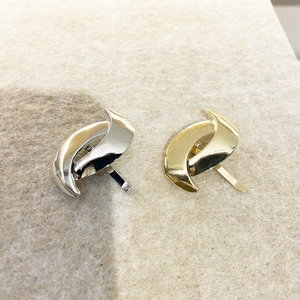 Close-up of minimalist gold and silver metallic curved hair pins on white felt