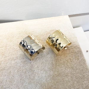Gros plan de larges bracelets manchettes martelés en finitions métalliques or et argent poli