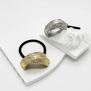 Close-up of textured gold and silver U-shaped alloy hair ties on a minimalist display