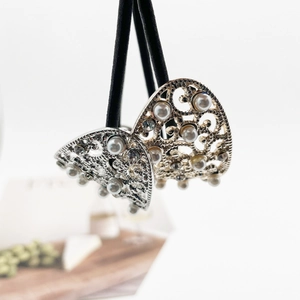 Detail of vintage silver alloy hair tie featuring hollow patterns and pearl embellishments