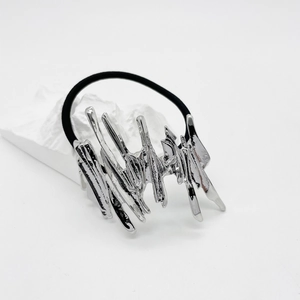 Detail of silver liquid metal alloy hair tie with irregular flowing shape on white background
