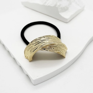 Detail shot of golden metal cuff hair tie with elegant brushed stripe texture on stone