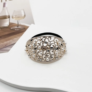 Close-up of gold hollow alloy hair tie with white pearls and rhinestones on white desk