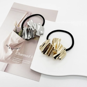 Detail showing gold and silver fluid metal charms on elastic hair ties in minimalist style