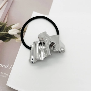 Detailed macro view of an irregular silver wrinkled metal hair tie on a white card background
