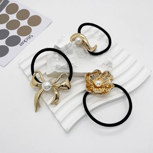 Gros plan de trois élastiques à cheveux noirs avec pendentifs dorés et perles blanches