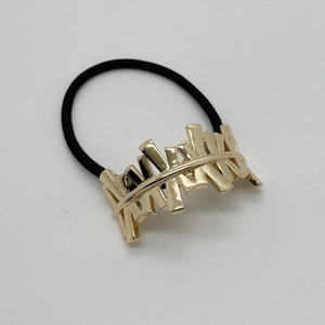 Detail of a shiny gold irregular U-shaped alloy accent on a black elastic hair tie