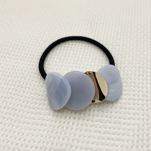 Detail of high-elastic hair tie with marble acrylic disks and golden metal accent