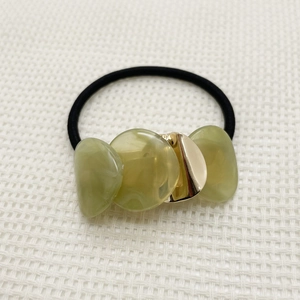 Detail of elastic hair tie with translucent green resin beads and golden metal accent