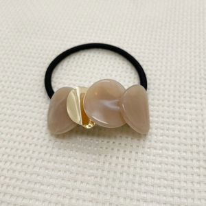 Detail of high-elasticity hair tie featuring beige resin discs and golden metal accents